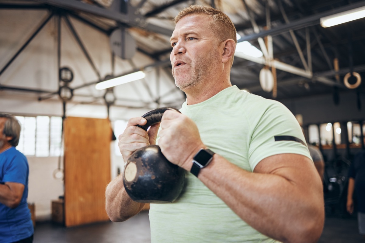 A man exercising with a kettlebell at the gym.